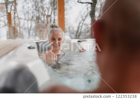 Bathing in hot tub during cold winter day. Older woman sitting in water and talking with husband. Bathing in hot tub during cold winter day. Older woman sitting in water and talking with husband. 122353238