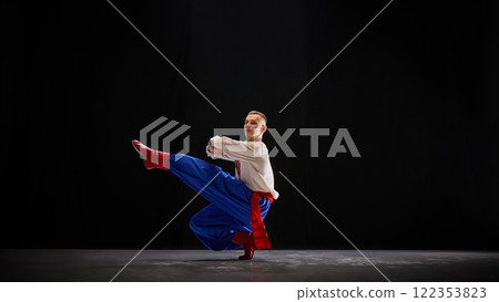 Ukrainian dancer in flowing motion, red boots and blue trousers creating dynamic contrast, expressing rhythm and connection to cultural roots. 122353823