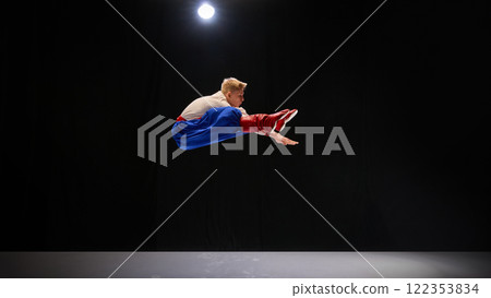 Performer in mid-air leap, dressed in blue trousers and embroidered shirt, arms extended in energetic motion, radiating joy and cultural pride. Performer in mid-air leap, dressed in blue trousers and embroidered shirt, arms extended in energetic motion, radiating joy and cultural pride. 122353834