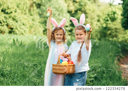 Easter egg hunt. Group Of Children Wearing Bunny Ears Running To Pick Up colorful Egg On Easter Egg Hunt In Garden. Easter tradition. Laughing children in park with basket spring concept 122354278