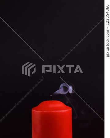 Red extinguished candle with smoke on black background 122354366