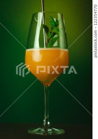 Refreshing Orange Cocktail with Mint Garnish in a Stylish Glass Vibrant Summer Drink Against Lush Greenery Refreshing Orange Cocktail with Mint Garnish in a Stylish Glass Vibrant Summer Drink Against Lush Greenery 122354770