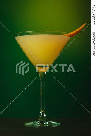 Refreshing Citrus Martini with Orange Garnish and Mint Vibrant Cocktail Against Lush Green Backdrop 122354772