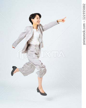 Middle-aged female business person pointing and jumping 122355882
