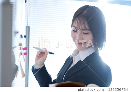Young businesswoman writing on a whiteboard Young businesswoman writing on a whiteboard 122356764
