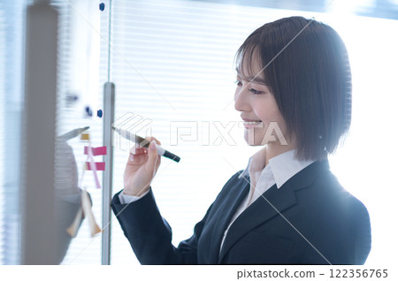 年輕的女商人在白板上寫字 122356765