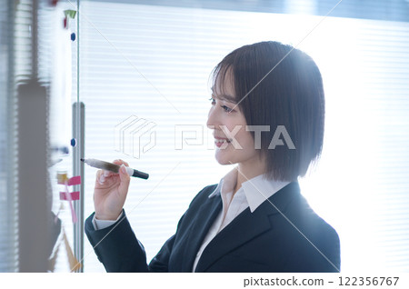 Young businesswoman writing on a whiteboard Young businesswoman writing on a whiteboard 122356767