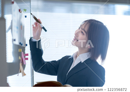 Young businesswoman writing on a whiteboard Young businesswoman writing on a whiteboard 122356872