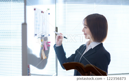 Young businesswoman writing on a whiteboard Young businesswoman writing on a whiteboard 122356873
