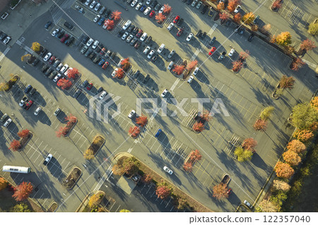 Aerial view of many colorful cars parked on parking lot with lines and markings for parking places and directions. Place for vehicles in front of a strip mall plaza 122357040