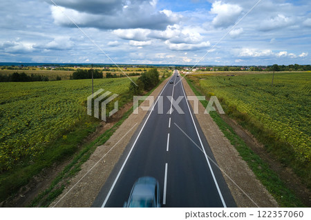 Aerial view of intercity road between green agricultural fields with fast driving cars. Top view from drone of highway traffic 122357060