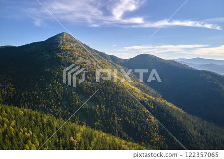 Aerial view of high hills with dark pine forest trees at autumn bright day. Amazing scenery of wild mountain woodland 122357065