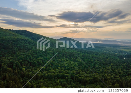 Aerial view of green pine forest with dark spruce trees covering mountain hills. Nothern woodland scenery from above Aerial view of green pine forest with dark spruce trees covering mountain hills. Nothern woodland scenery from above 122357069