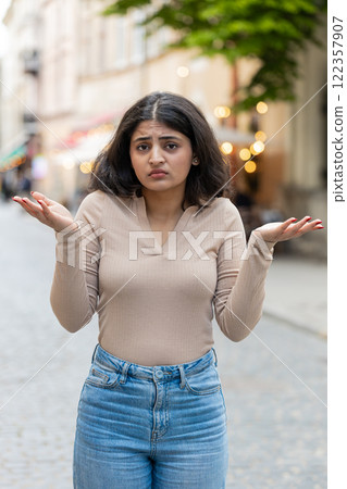 Surprised frustrated Indian woman raising hands asking reason of failure, demonstrating disbelief 122357907