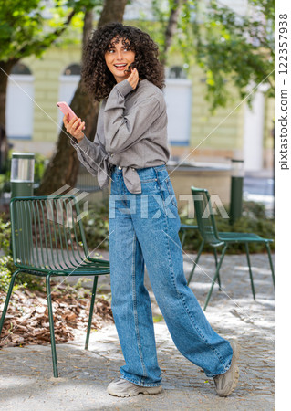 Tourist young curly hair woman using smartphone typing text messages looking for search a way on map 122357938