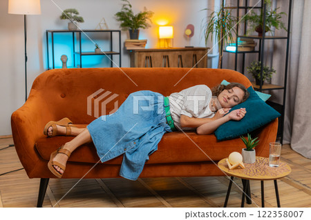 Happy young Caucasian woman enjoying sleeping relaxing rest on sofa couch in living room at home 122358007