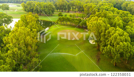 An aerial view of a golf course with vibrant greenery and a tranquil water feature 122358031