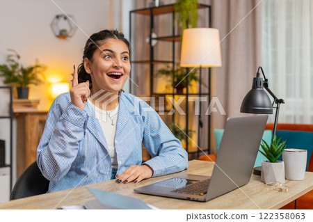Young Indian woman freelancer prepares startup project for presentation finds idea at table at home Young Indian woman freelancer prepares startup project for presentation finds idea at table at home 122358063