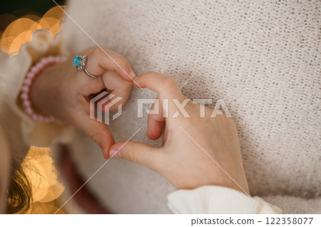 Heart-Shaped Gesture Between Child and Adult in Warm Holiday Setting 122358077