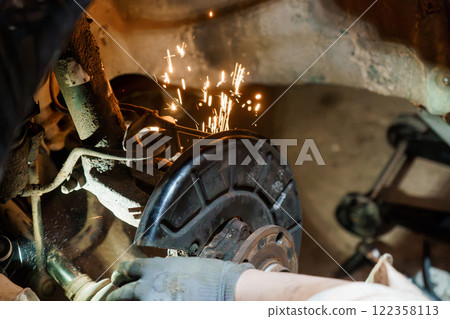 Mechanic Working on Car Brake System with Sparks Flying Mechanic Working on Car Brake System with Sparks Flying 122358113