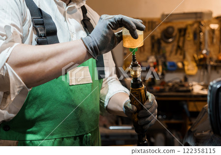 Skilled Craftsman Carefully Adding Oil to Vintage Tool in Workshop Skilled Craftsman Carefully Adding Oil to Vintage Tool in Workshop 122358115