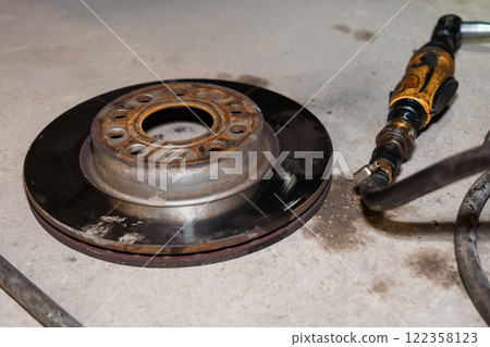 Rusty Brake Rotor with Air Tool on a Grimy Garage Floor Rusty Brake Rotor with Air Tool on a Grimy Garage Floor 122358123