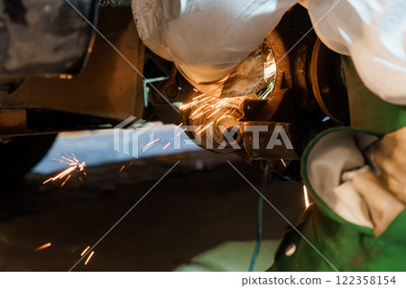Skilled Mechanic Performing Precision Metal Work with Sparks in Automotive Repair Shop 122358154
