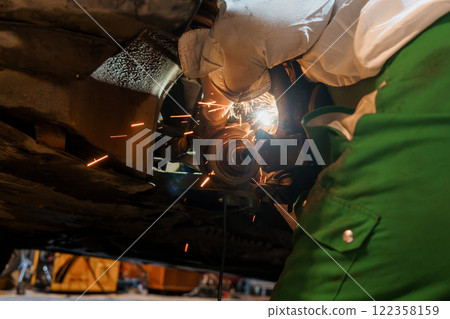 An Automotive Technician Working on a Car's Mechanical Components with Sparks Flying An Automotive Technician Working on a Car's Mechanical Components with Sparks Flying 122358159