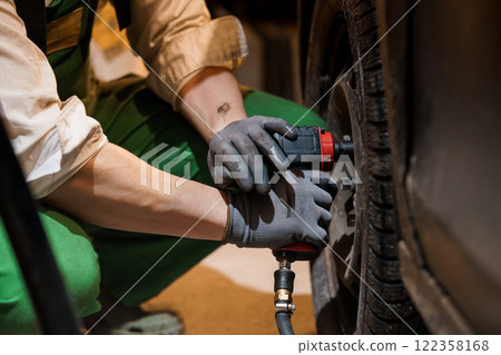 Mechanic Using Air Tool to Change Tire in Workshop 122358168