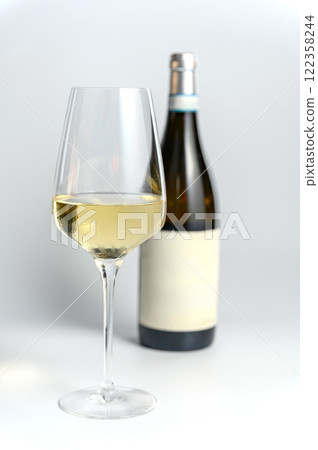 Glass of Red Wine with Bottle in Background on White. Glass of Red Wine with Bottle in Background on White. 122358244