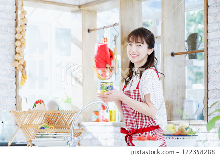 A woman in an apron cooking in the kitchen A woman in an apron cooking in the kitchen 122358288