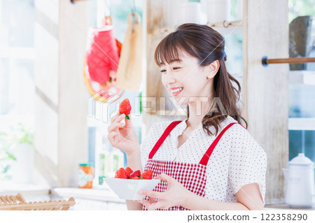 A woman picking and eating strawberries in the kitchen A woman picking and eating strawberries in the kitchen 122358290
