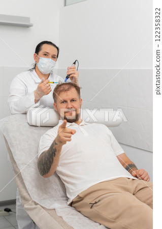 Trichologist doing man improve hair growth procedure, dermapen microneedling, vitamin injections 122358322