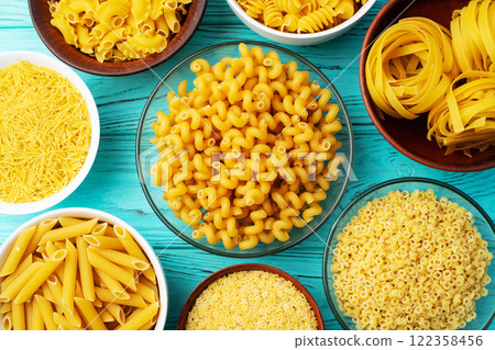 Assorted Uncooked Pasta in Bowls on Wooden Table 122358456