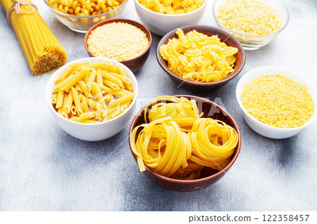 Assorted Uncooked Pasta in Bowls on Wooden Table 122358457