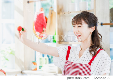 一個女人在廚房裡採摘和吃草莓 122358590