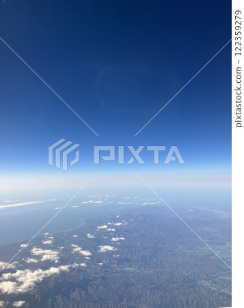A photo taken from an airplane shows the sky, sea, and land. A photo taken from an airplane shows the sky, sea, and land. 122359279