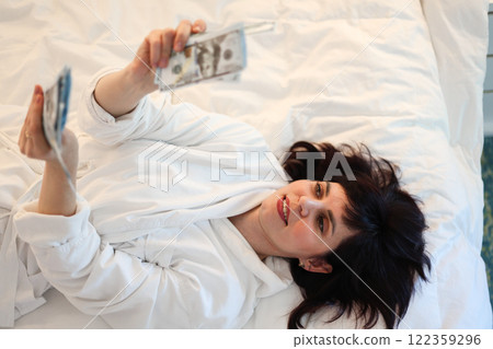 Unexpected profit, woman happy with big sum of money, lying on her back in bed Unexpected profit, woman happy with big sum of money, lying on her back in bed 122359296