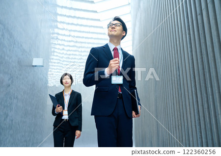A business person in a suit walking down a corridor 122360256