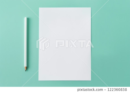 An overhead view of a regular pencil next to a blank sheet of white textured watercolor paper on a light green background. Suitable for advertising related to creativity, art, education and stationery 122360838