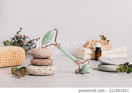 Jade facial massager, spa items and pebbles on table 122361051