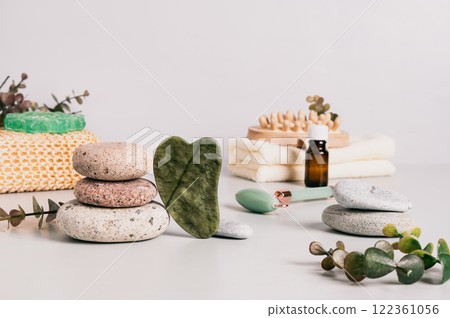 Jade gua sha massager, pebbles and spa items on table 122361056