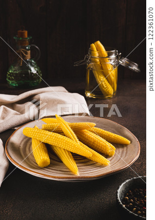Canned mini corn cobs on a plate on a table vertical view Canned mini corn cobs on a plate on a table vertical view 122361070