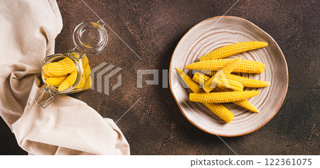 Portion of canned corn on the cob on a plate and in a jar on a table top view web banner Portion of canned corn on the cob on a plate and in a jar on a table top view web banner 122361075