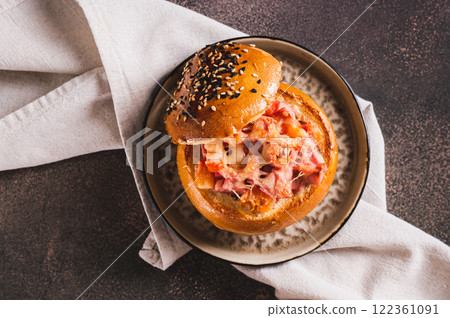 Baked burger with sausages, tomatoes, cheese and egg on a plate on a table top view 122361091