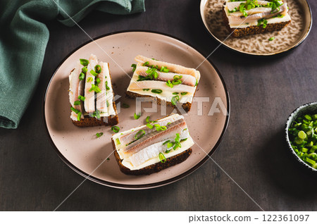 Norwegian smorrebrod made from rye bread, butter and salted herring on a plate on a table 122361097