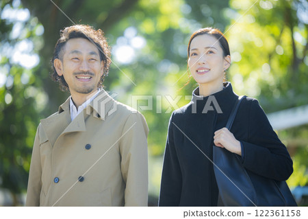 A couple in coats walking down the sidewalk 122361158