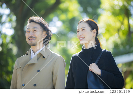 A couple in coats walking down the sidewalk 122361159