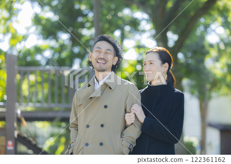 A couple in coats walking down the sidewalk 122361162