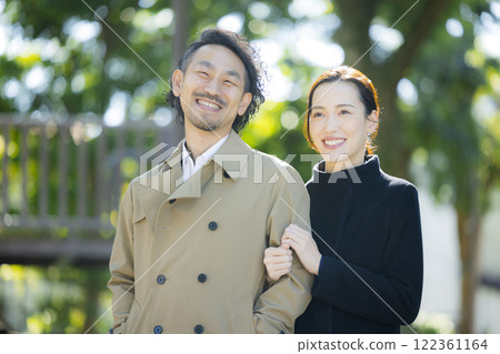 A couple in coats walking down the sidewalk 122361164
